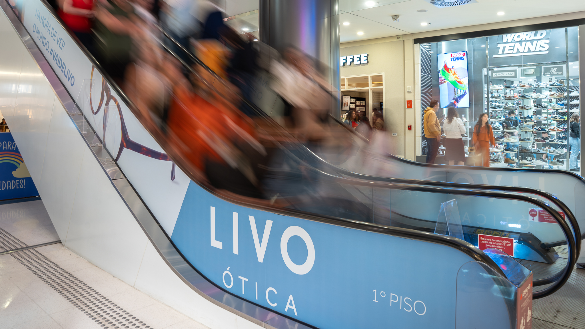 Mídia OOH em lateral de escada rolante de shopping com campanha Livo Ótica no 1º piso