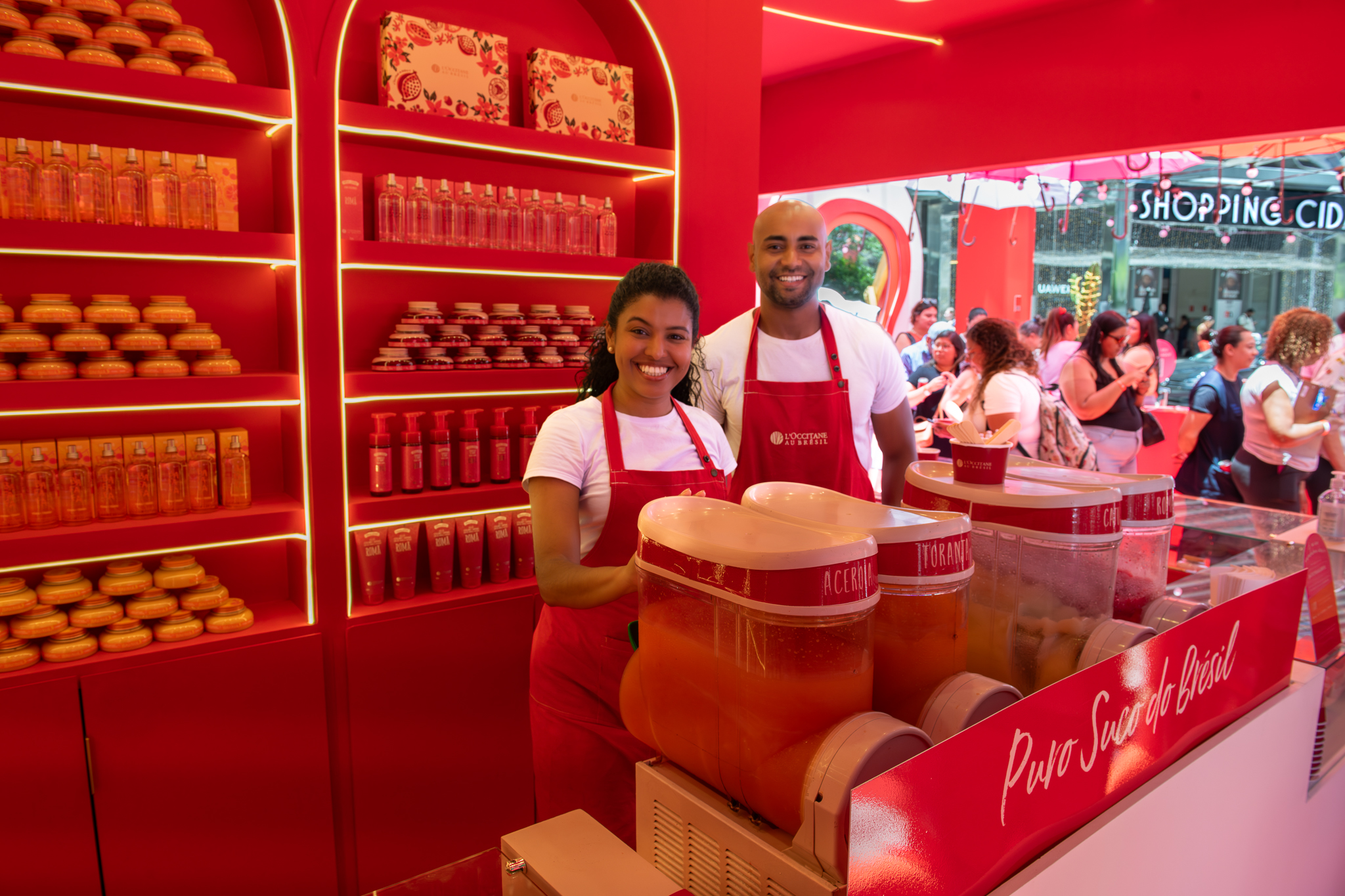Equipe da L'Occitane au Brésil atendendo consumidores em loja pop-up com produtos e sucos naturais.